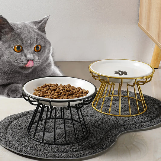 Grey cat eating from a white ceramic dish on a black iron stand