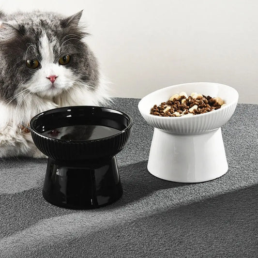 Black and white fluted pedestal cat bowls with a cat beside them