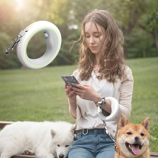 Woman sitting on grass holding the white ring leash with a Samoyed and a Shiba Inu beside her