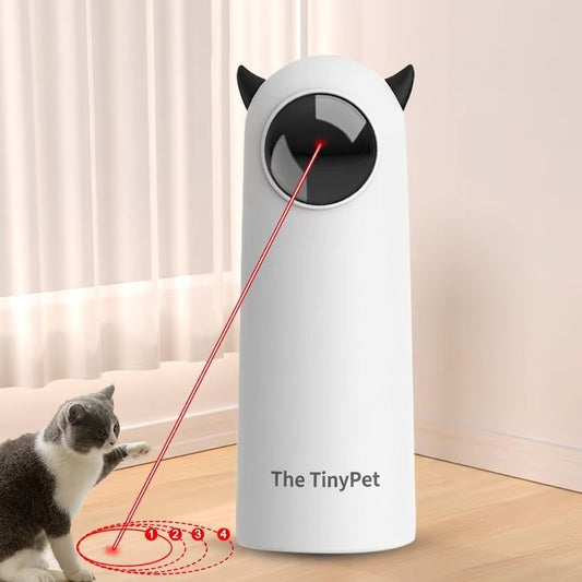 Grey cat pawing at a red dot projected in circles on the floor by the white laser toy