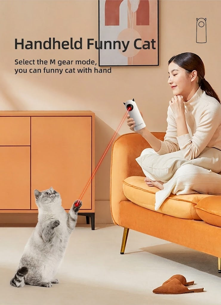 A woman on a sofa holding the toy in hand-held mode while a cat chases the dot