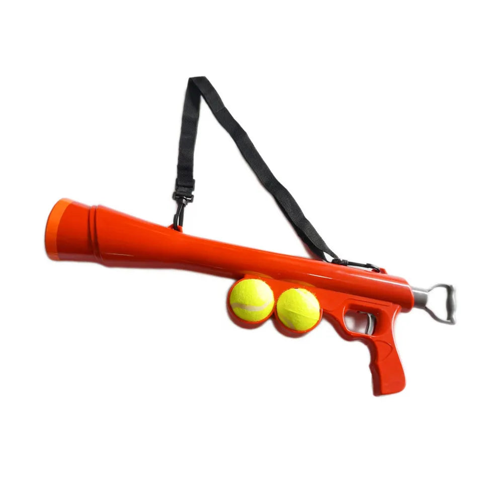 The red launcher with its shoulder strap and two tennis balls