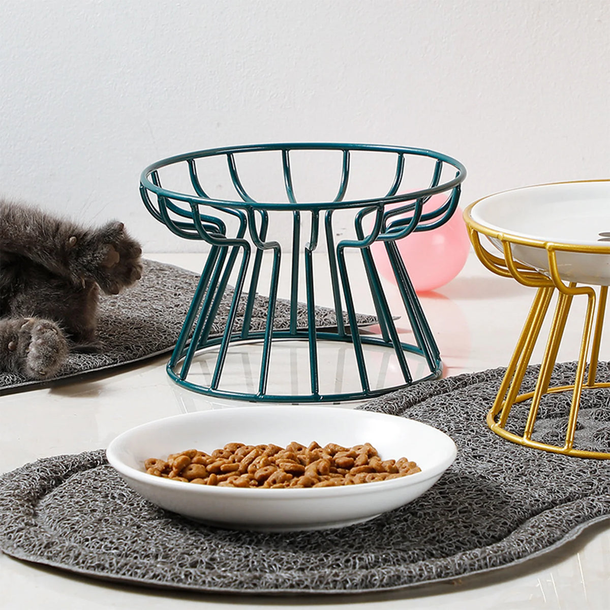Cat beside two elevated dishes on a grey mat