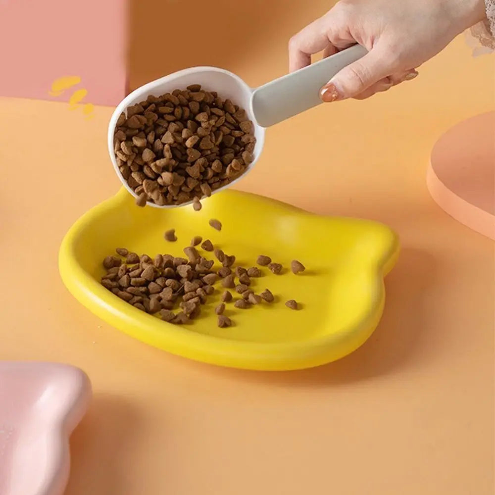 Dry food being poured into a yellow cat-shaped dish