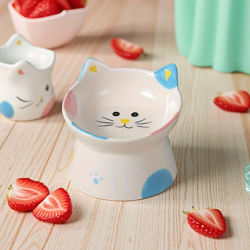 Cat-face bowl with blue ears beside a white cat