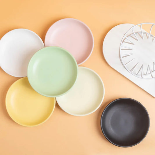 Ceramic plates in several colours beside a white wire stand