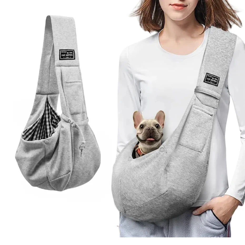 Person wearing the grey crossbody sling with a small dog looking out of the front pouch