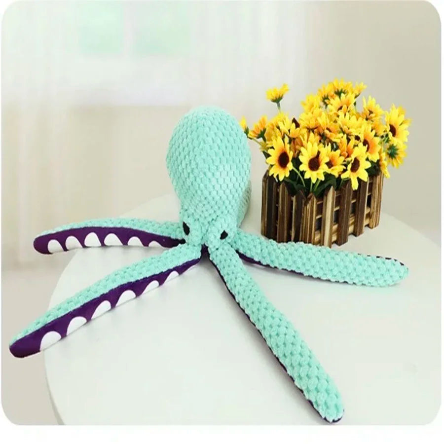 The octopus toy on a table beside a jar of sunflowers