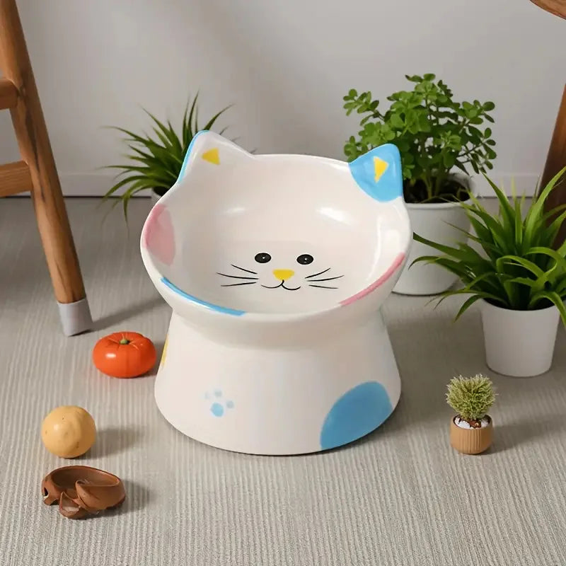 Cat-face raised ceramic bowl with blue ears beside houseplants