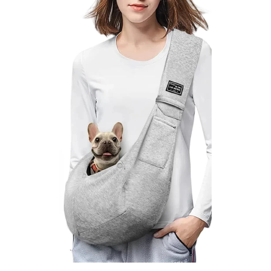 Woman wearing the grey crossbody sling with a French bulldog looking out of the front pouch